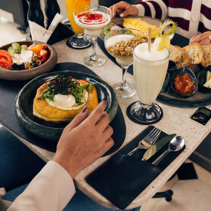 Table du petit-déjeuner : jus, yaourt au granola, plat à l’œuf et pain