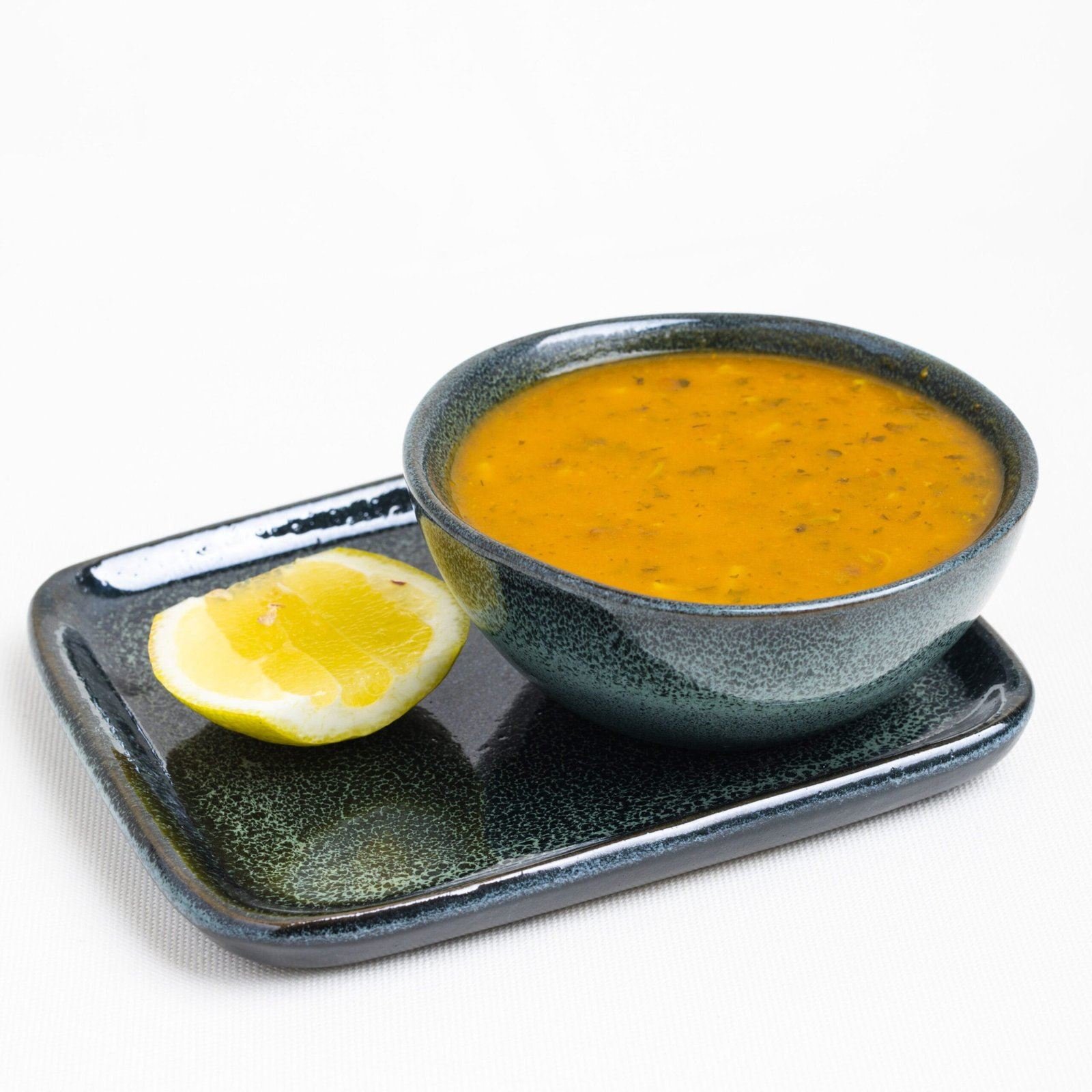 Bol de soupe orangée servi avec un quartier de citron