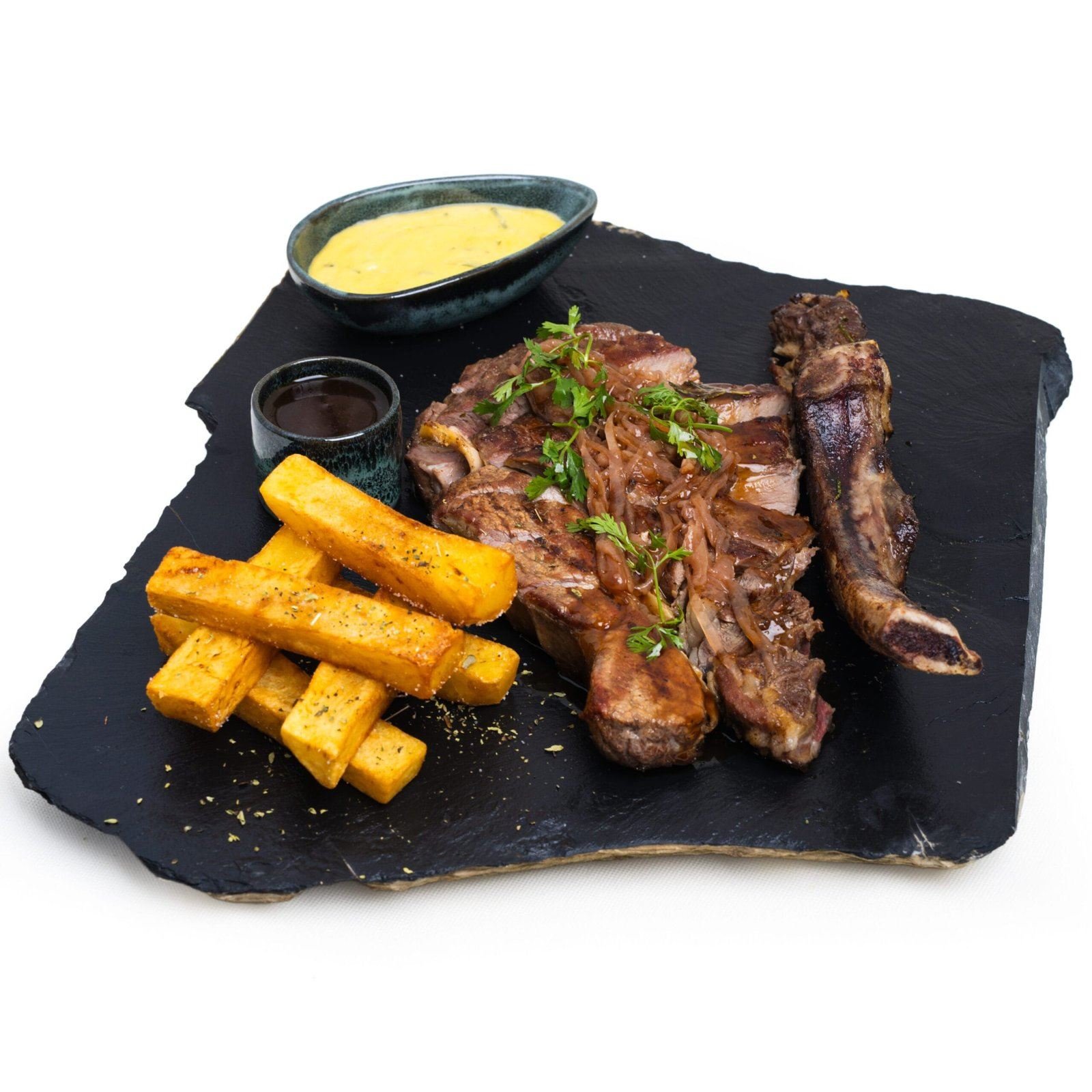 Côte grillée avec frites épaisses et sauces, servie sur une ardoise