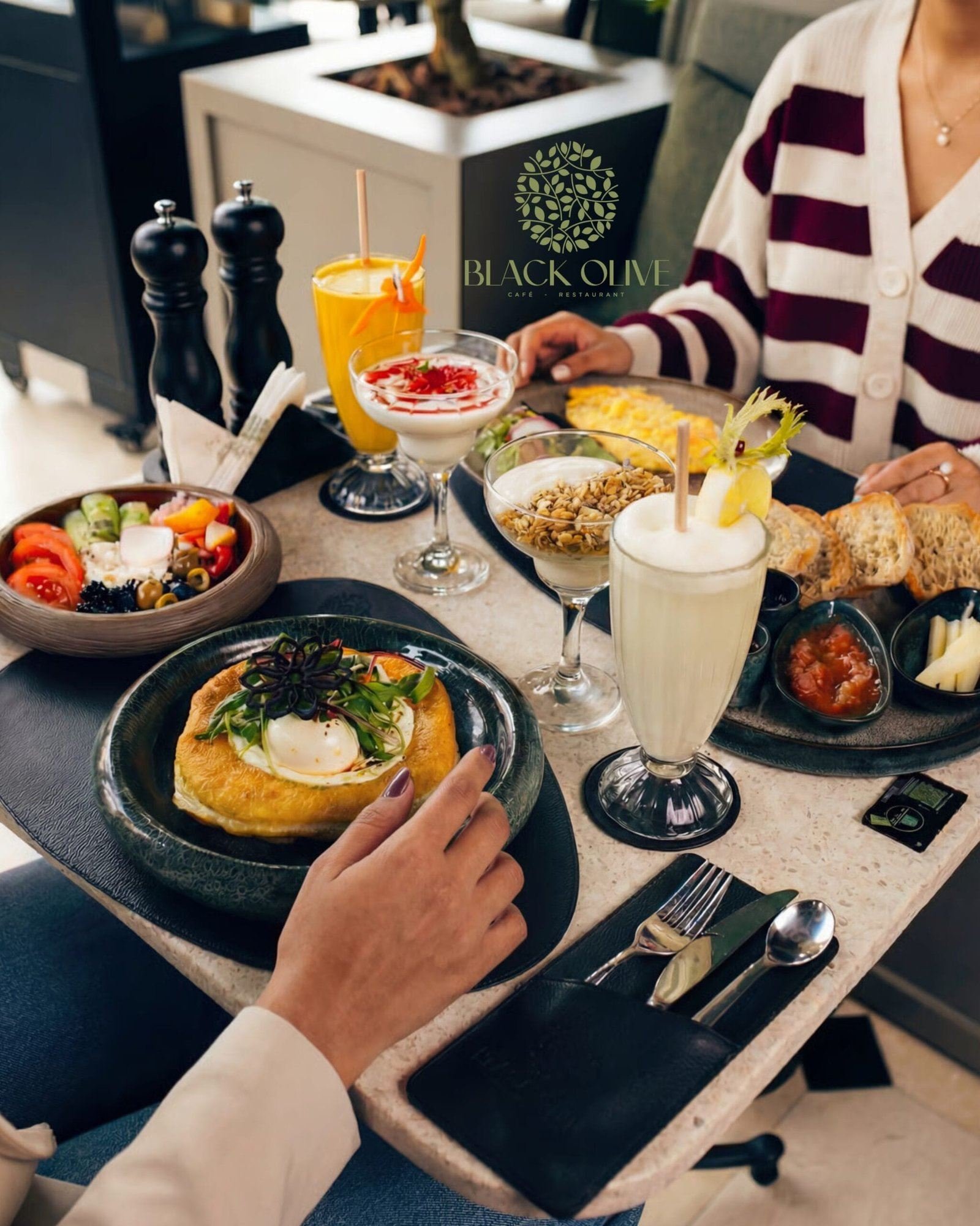 Une table de petit déjeuner vue d'en haut, verres de jus d'orange et plats partagés